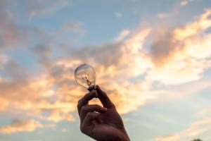 Human hand holding a lamp against the sky background